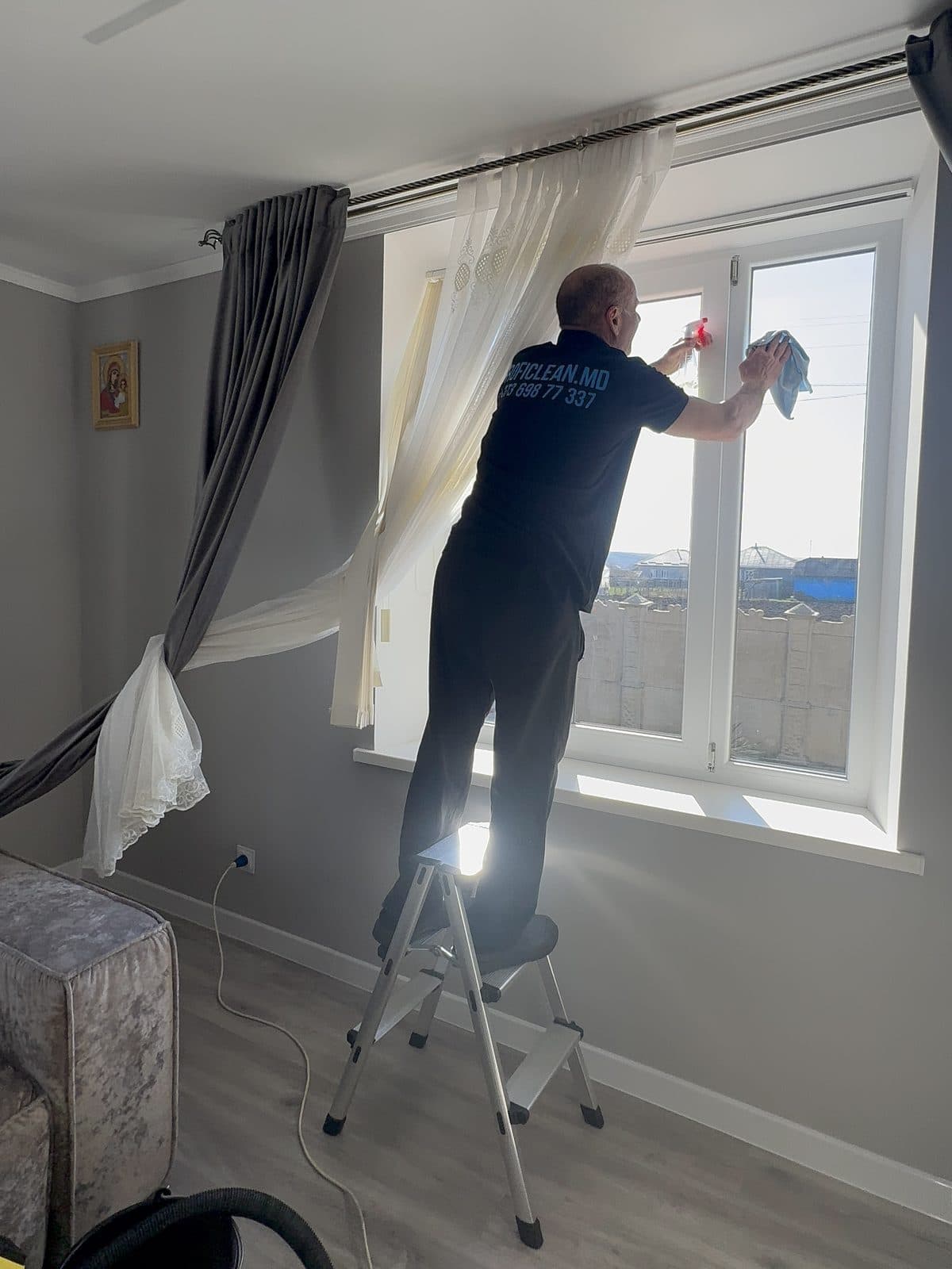 Coleg ProfiClean spală fereastra la un client acasă, de pe scăriță